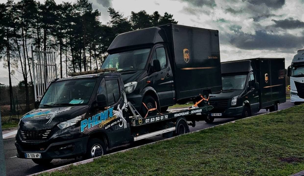 Dépanneuse Phenix Assistance remorquant un véhicule utilitaire UPS sous la pluie